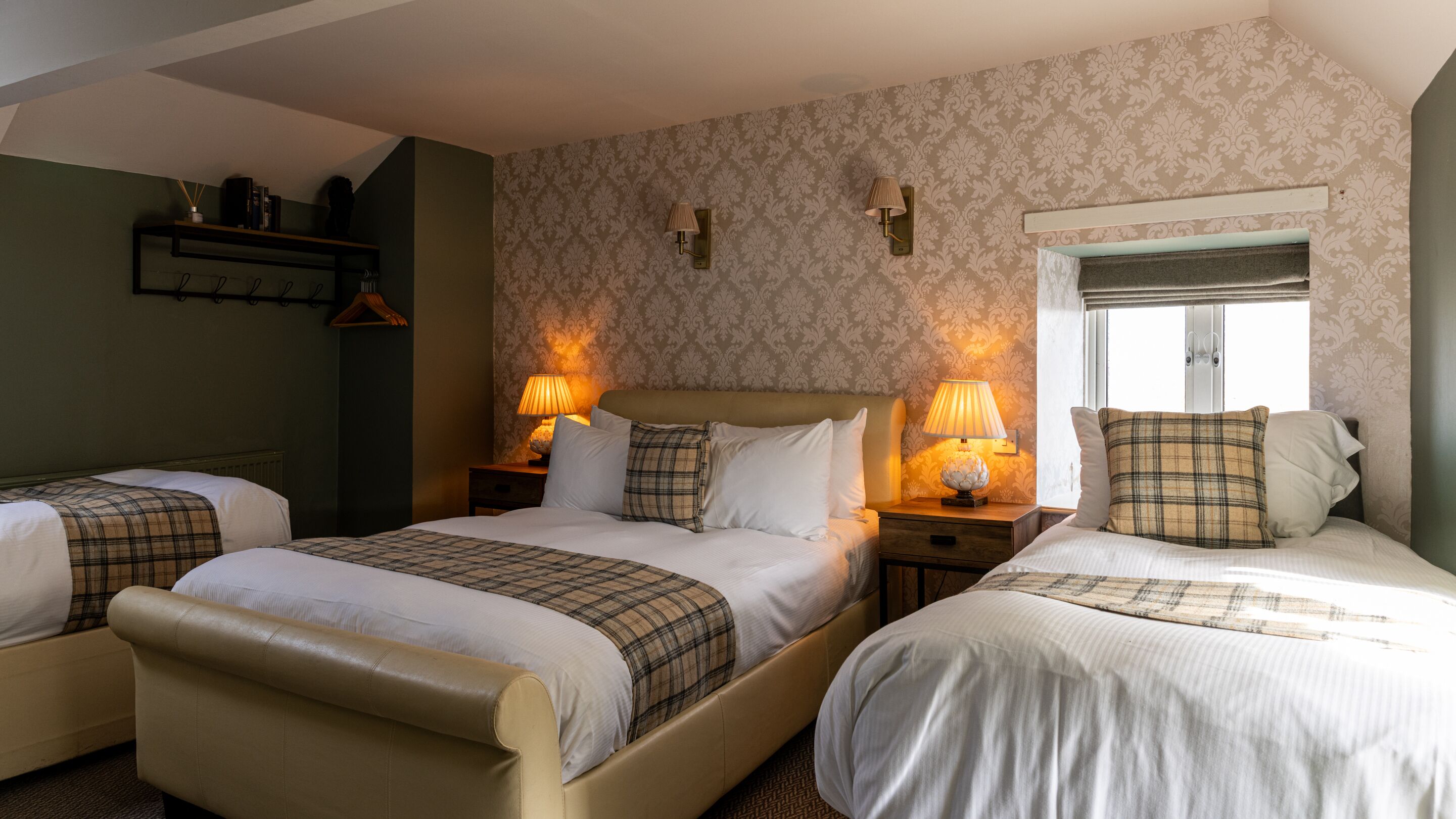 A hotel room with two beds, a window, and a lamp on each nightstand.