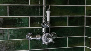 Une salle de bain avec un robinet chromé, une poignée blanche et un thermomètre indiquant les réglages de température.