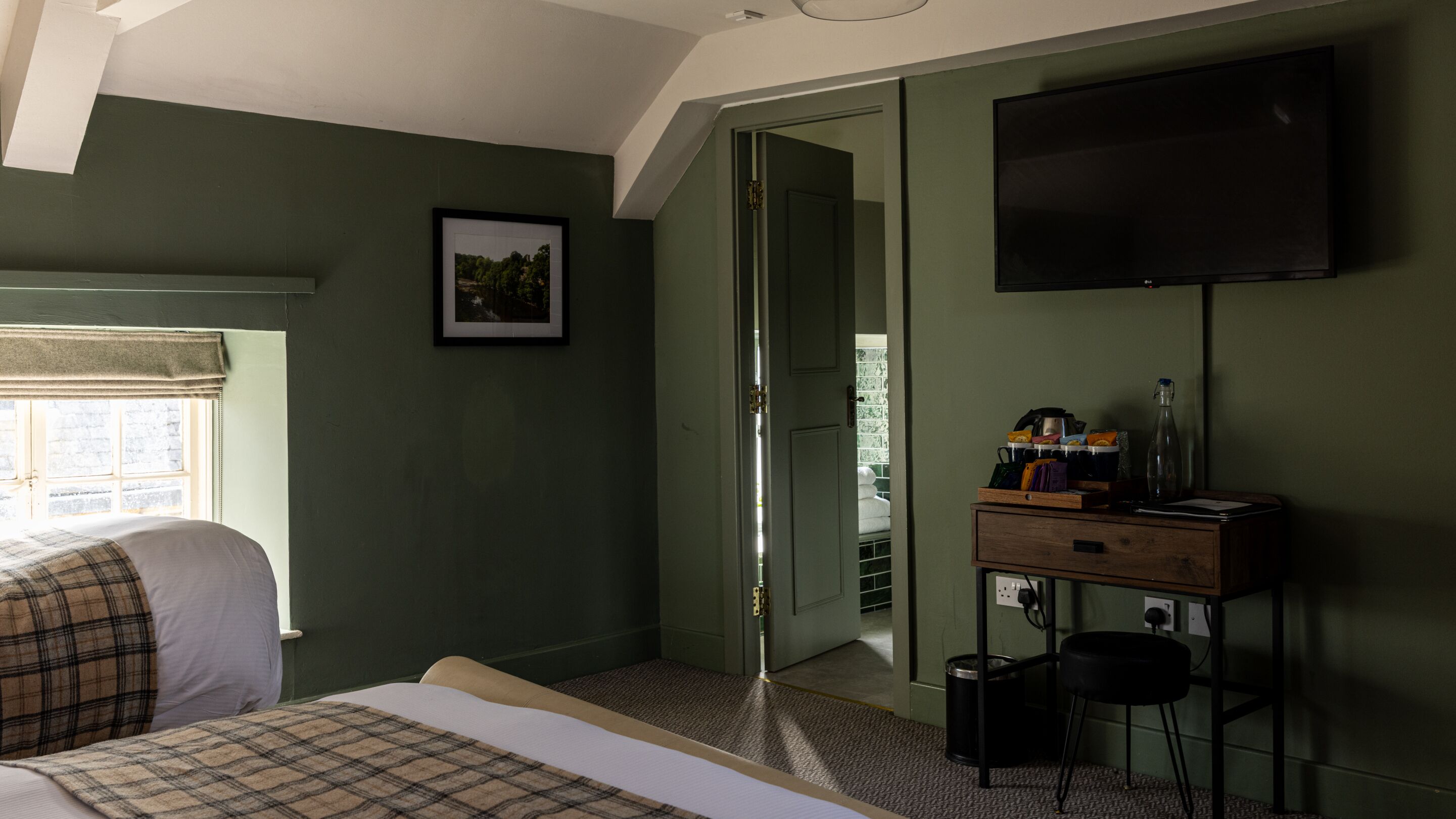 Une chambre à coucher comprenant un lit, une télévision, un bureau avec une chaise et une porte donnant sur une autre pièce.