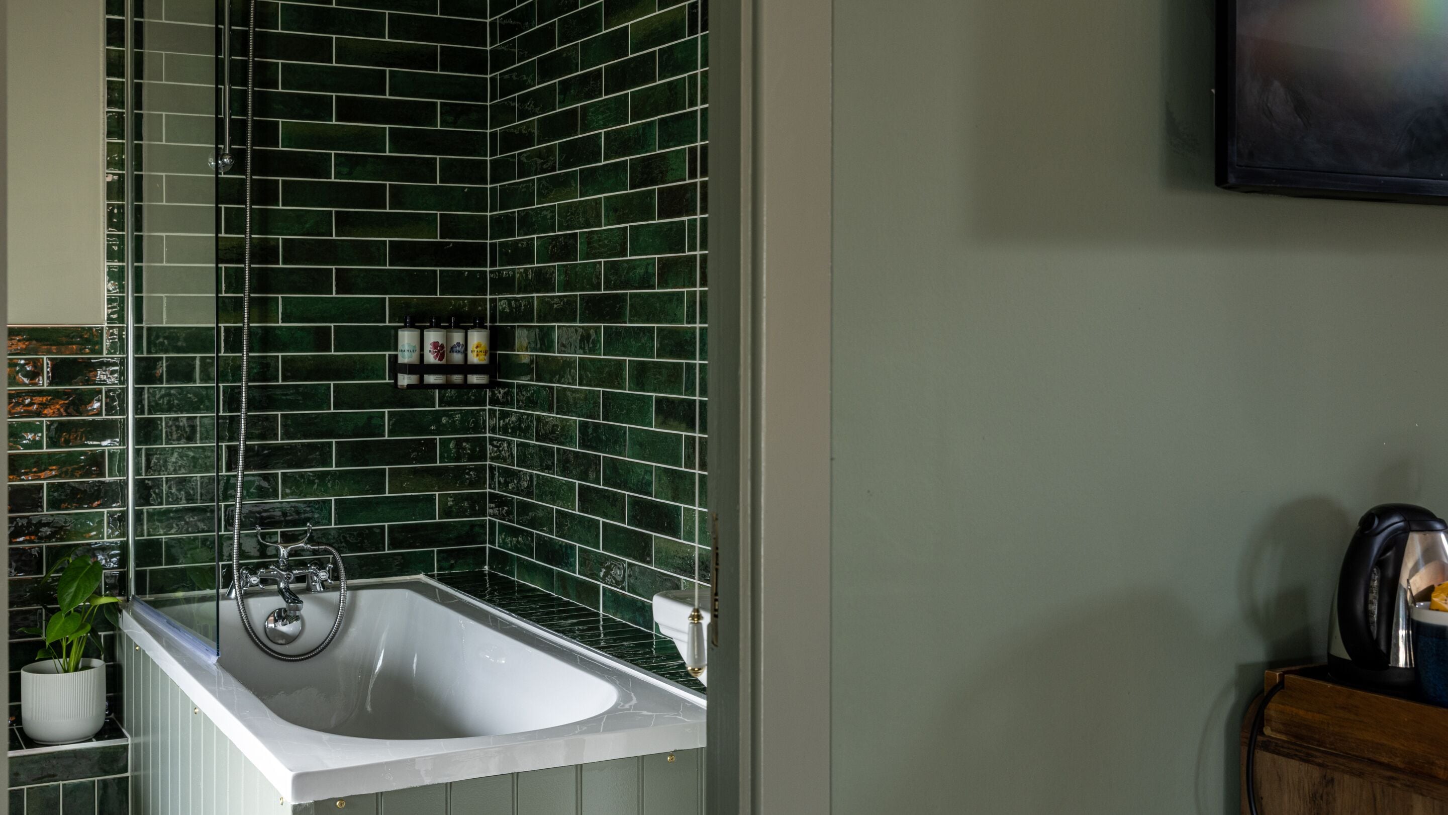 A bathroom with a white sink, green tiled walls, and a shower.