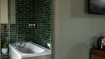 A bathroom with a white sink, green tiled walls, and a shower.