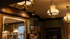 Een bar met een bord waarop 'THE BLACK LION' staat en een ander bord dat 'BAR SNACKS' adverteert voor £15.