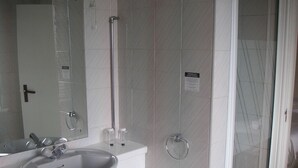 A bathroom with a white sink, mirror, and shower. - The Bridge Hotel (Scunthorpe)