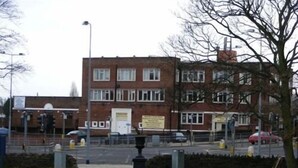 A multi-story building with a brick facade, a central entrance, and a small garden area with a pathway leading to it. - The Bridge Hotel (Scunthorpe)