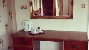A wooden desk with a mirror above it, a tray with a white kettle and cups, and a floral wallpaper pattern on the wall. - The Bridge Hotel (Scunthorpe)