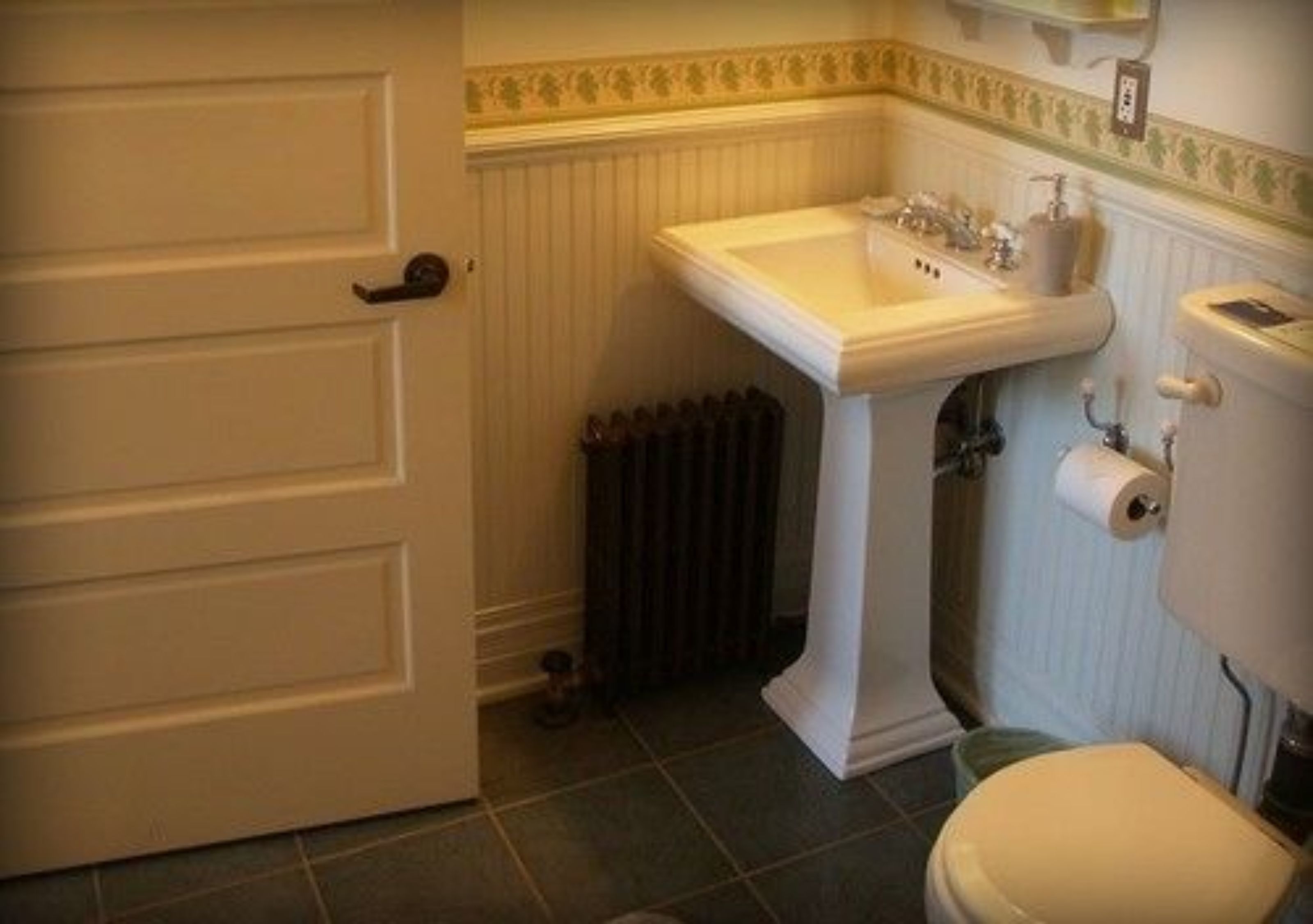 A bathroom with a white sink, toilet, and radiator.
