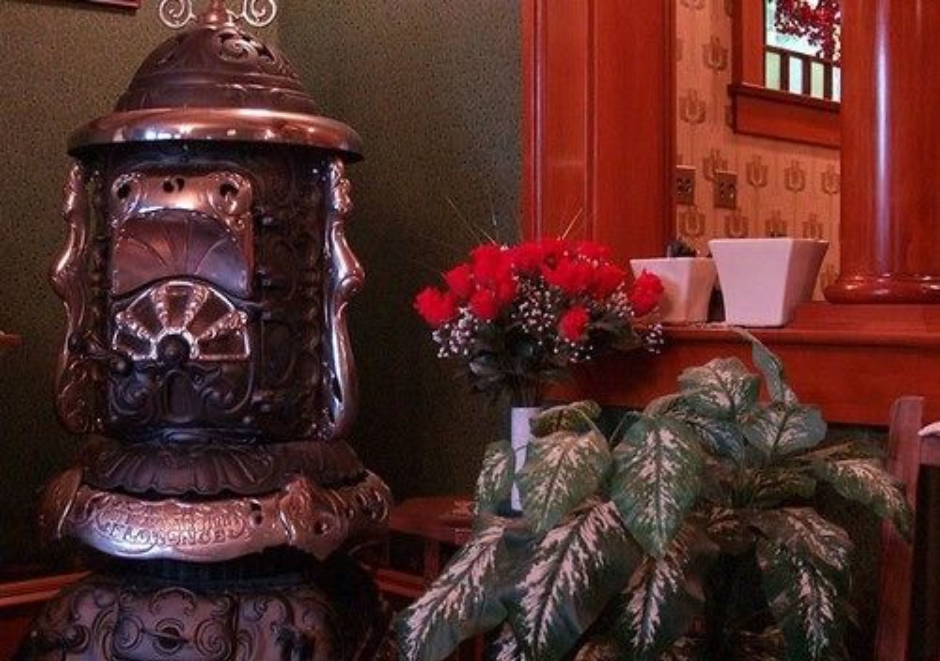 A decorative metal sculpture, a potted plant with variegated leaves, and a vase with red flowers.