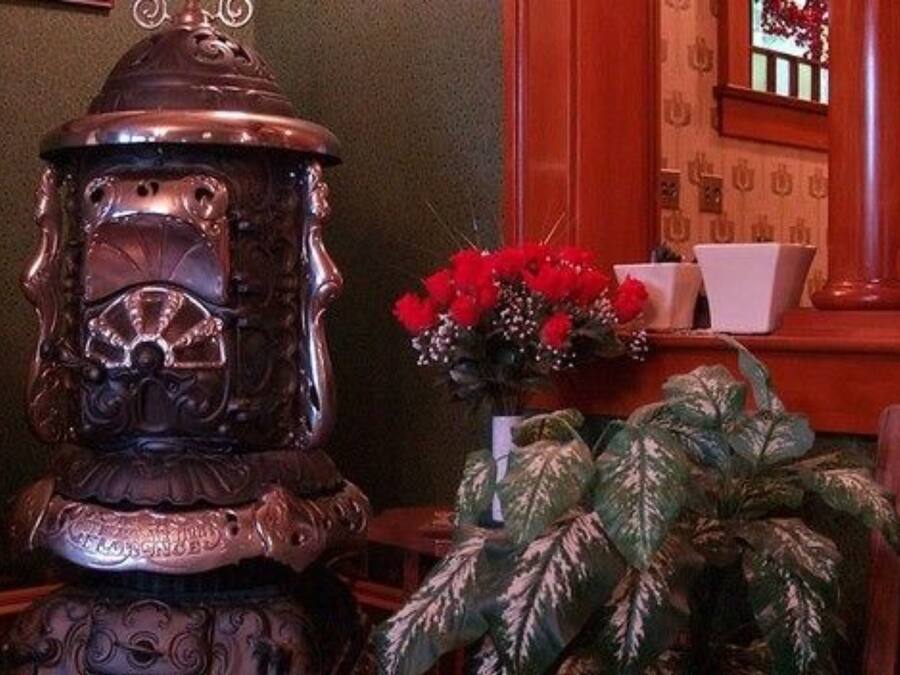 A decorative metal sculpture, a potted plant with variegated leaves, and a vase with red flowers.