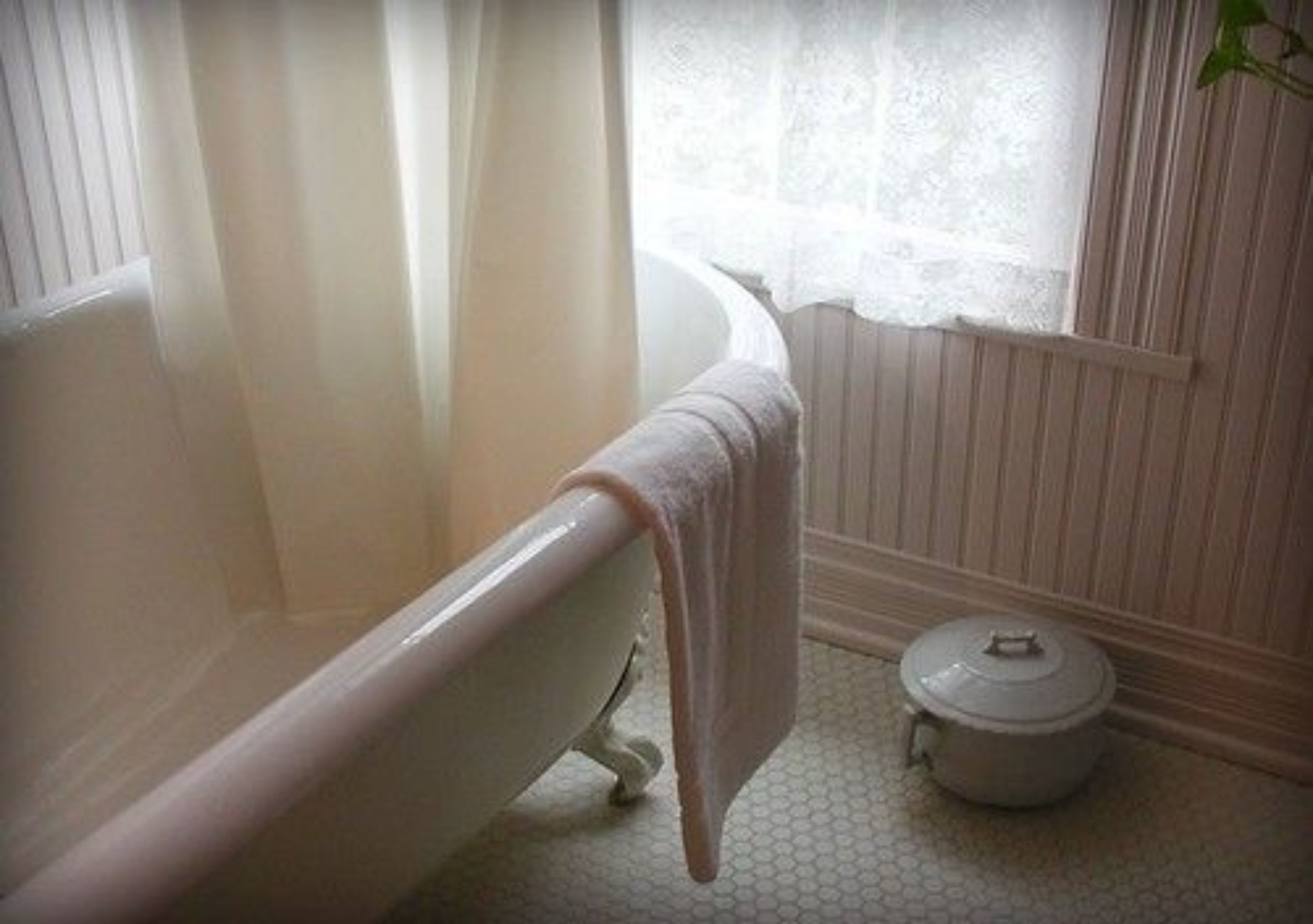 A bathroom with a bathtub, a white radiator, and a small white pot on the floor.