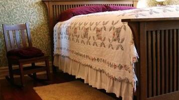 A bedroom with a wooden bed, a chair, and a patterned wall.