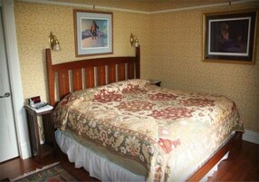 Ein Schlafzimmer mit einem hölzernen Bett, einer blumigen Bettdecke, zwei Wandlampen und zwei gerahmten Bildern.