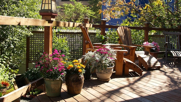 A wooden deck with outdoor furniture, potted plants, and a decorative lantern. - Alaskas Capital Inn Bed & Breakfast (Juneau)