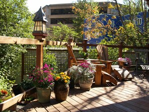 Une terrasse en bois agrémentée de meubles d’extérieur, de plantes en pot et d’une lanterne décorative.