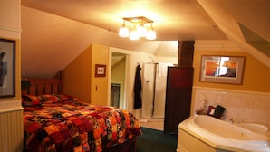A bedroom with a large bed, a walk-in closet, a bathroom with a bathtub, and a shower. - Alaskas Capital Inn Bed & Breakfast (Juneau)