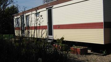 A single-story mobile home with a beige exterior and a red stripe.