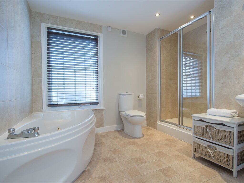 A modern bathroom with a freestanding bathtub, a toilet, and a glass-enclosed shower area.