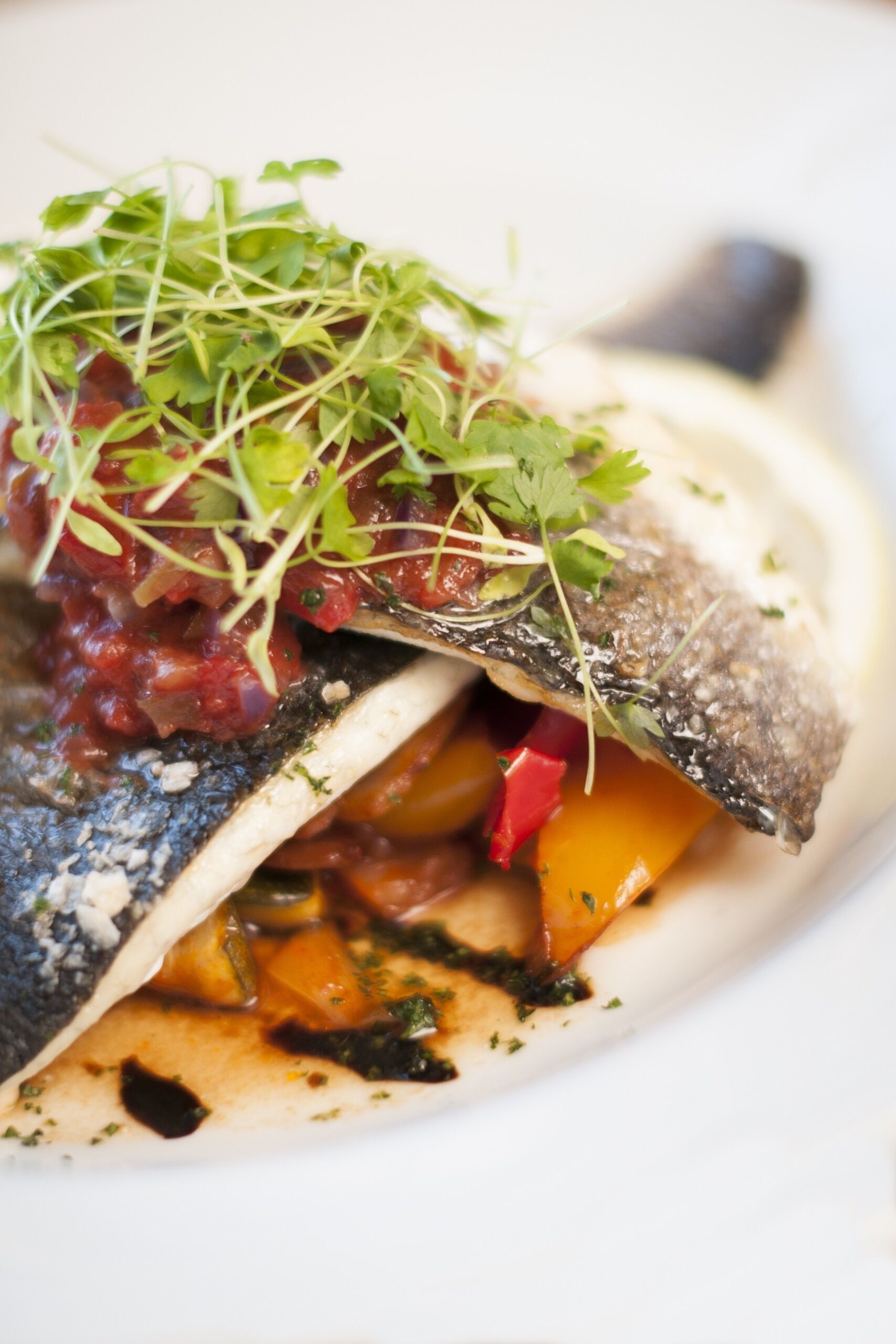Un piatto con pesce, verdure e guarnizione.