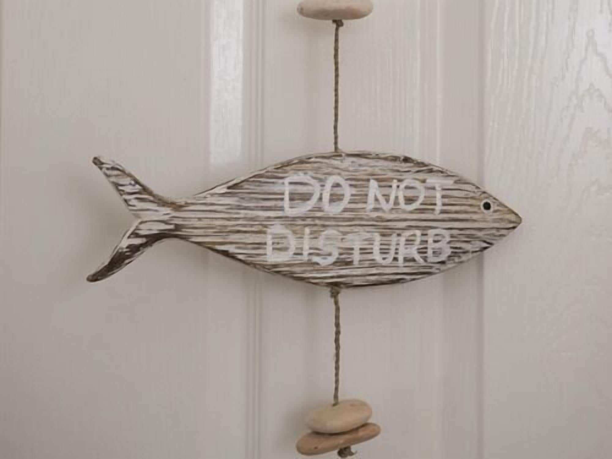Una decoración con forma de pez que muestra la frase 'DO NOT DISTURB' en una pared.