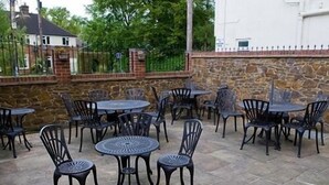 An outdoor patio with stone flooring and metal tables and chairs. - The Heath Inn (Leighton Buzzard)