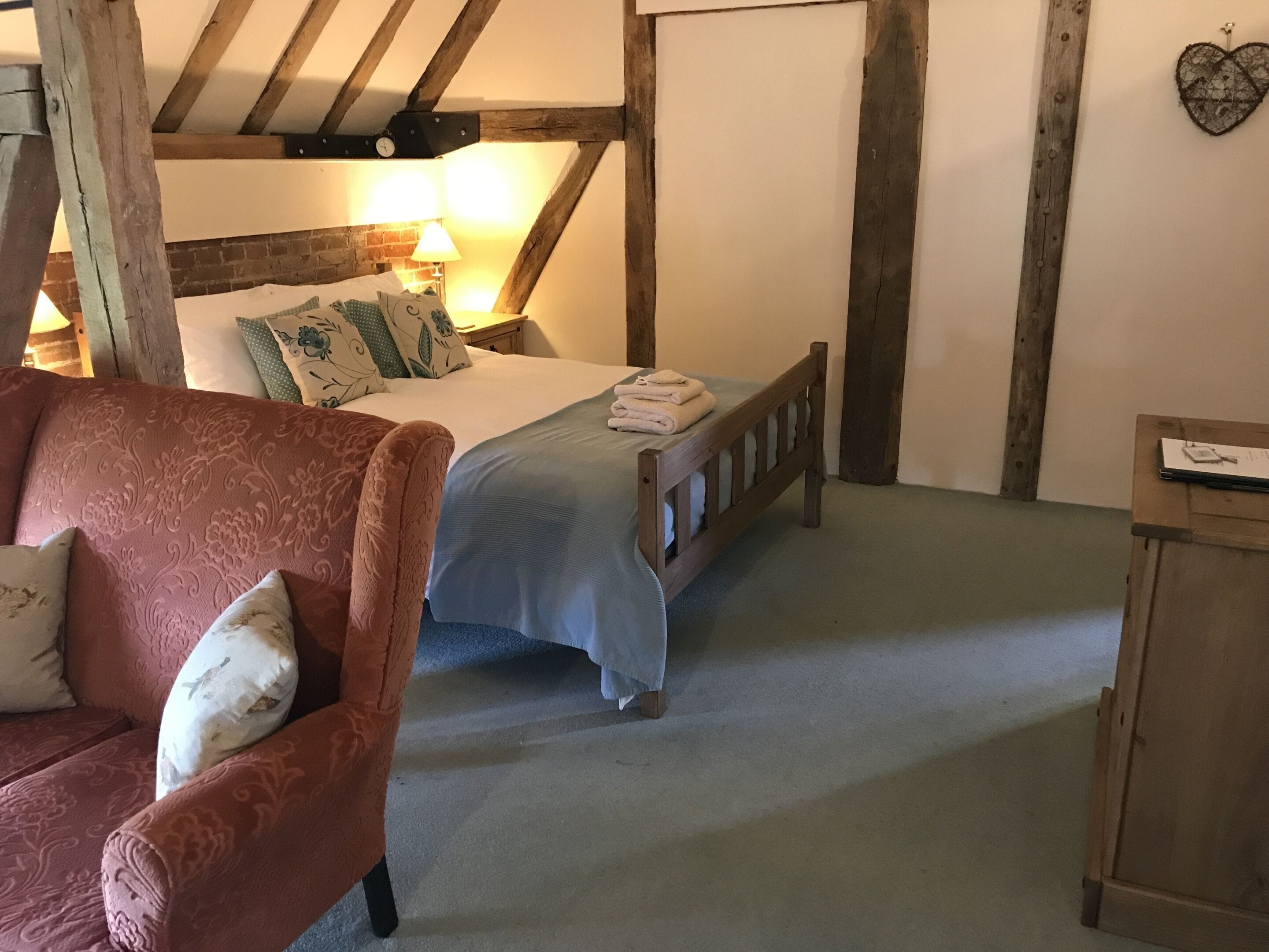 Un dormitorio acogedor con una cama, una silla de madera y una mesita de noche.