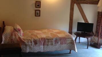 Un dormitorio con una cama, un televisor sobre una mesita y cuadros en la pared.