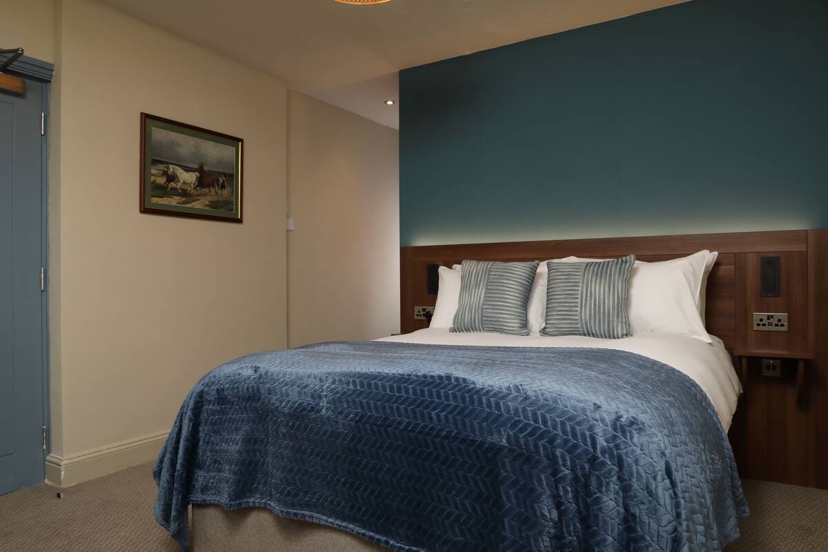 Une chambre à coucher avec un lit, un mur bleu et un tableau accroché au mur.