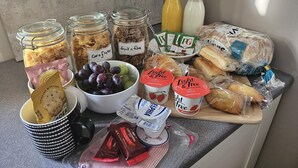 A breakfast spread with cereals, fruit, bread, and dairy products on a kitchen counter. - Wayside (Norwich)