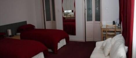 A hotel room with two beds, a white sofa, a desk, and a chair.