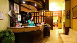 A hotel reception area with a curved reception desk, a seating area with a white sofa, and a sign reading "SALA PRANZO". - Hotel Agli Olmi (San Biagio di Callalta)