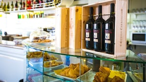 A bar area with wooden boxes labeled 'Castello Carboncino' containing bottles of wine, and a glass display case with pastries. - Hotel Agli Olmi (San Biagio di Callalta)