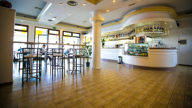 A spacious bar area with a curved counter, multiple stools, and a variety of bottles and glasses on display. - Hotel Agli Olmi (San Biagio di Callalta)