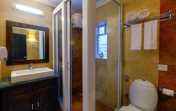 A bathroom with a sink, mirror, shower, and toilet.