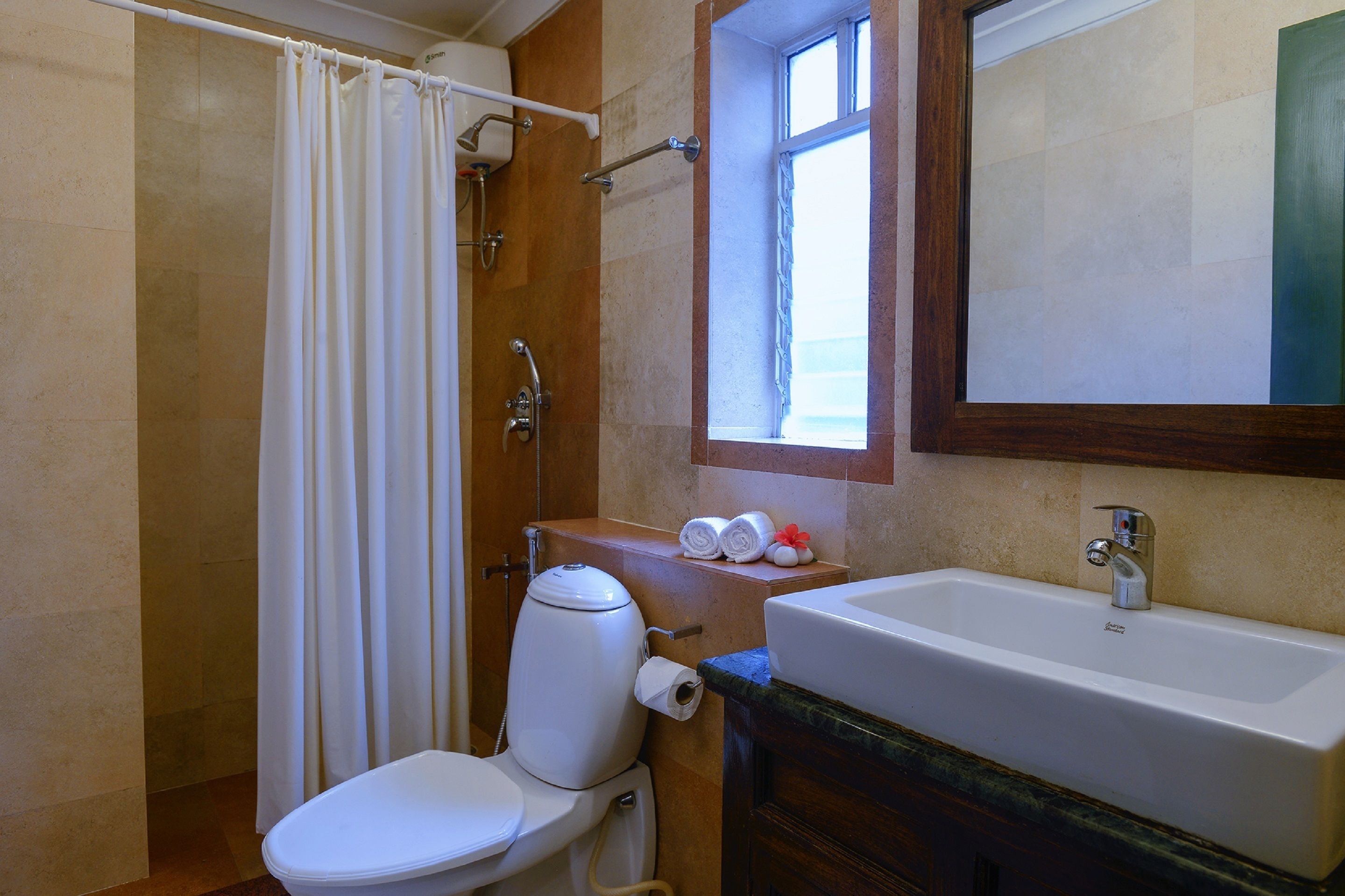 A bathroom with a toilet, shower, sink, and a window.