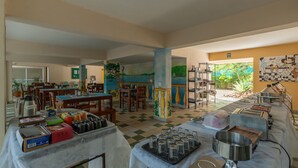 Un comedor con mesas y sillas, una barra de buffet y un mural en la pared.