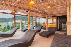 A covered outdoor seating area with wicker furniture and hanging lamps.