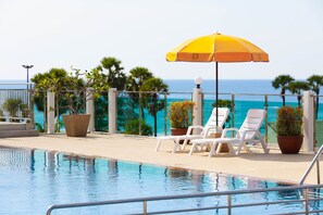 A poolside area with a view of the ocean, lounge chairs, and potted plants. - Baumancasa Beach Resort (Karon)