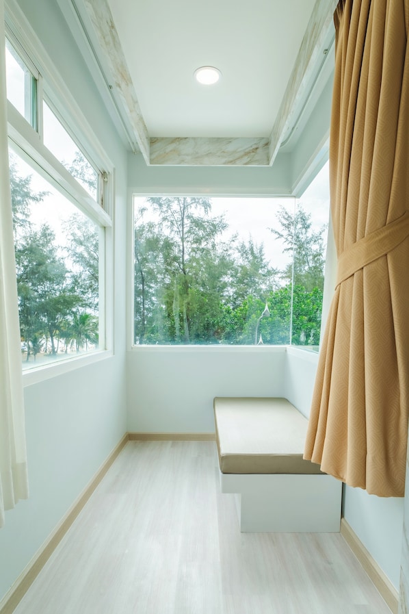 A room with a large window, a bench, and a view of trees.