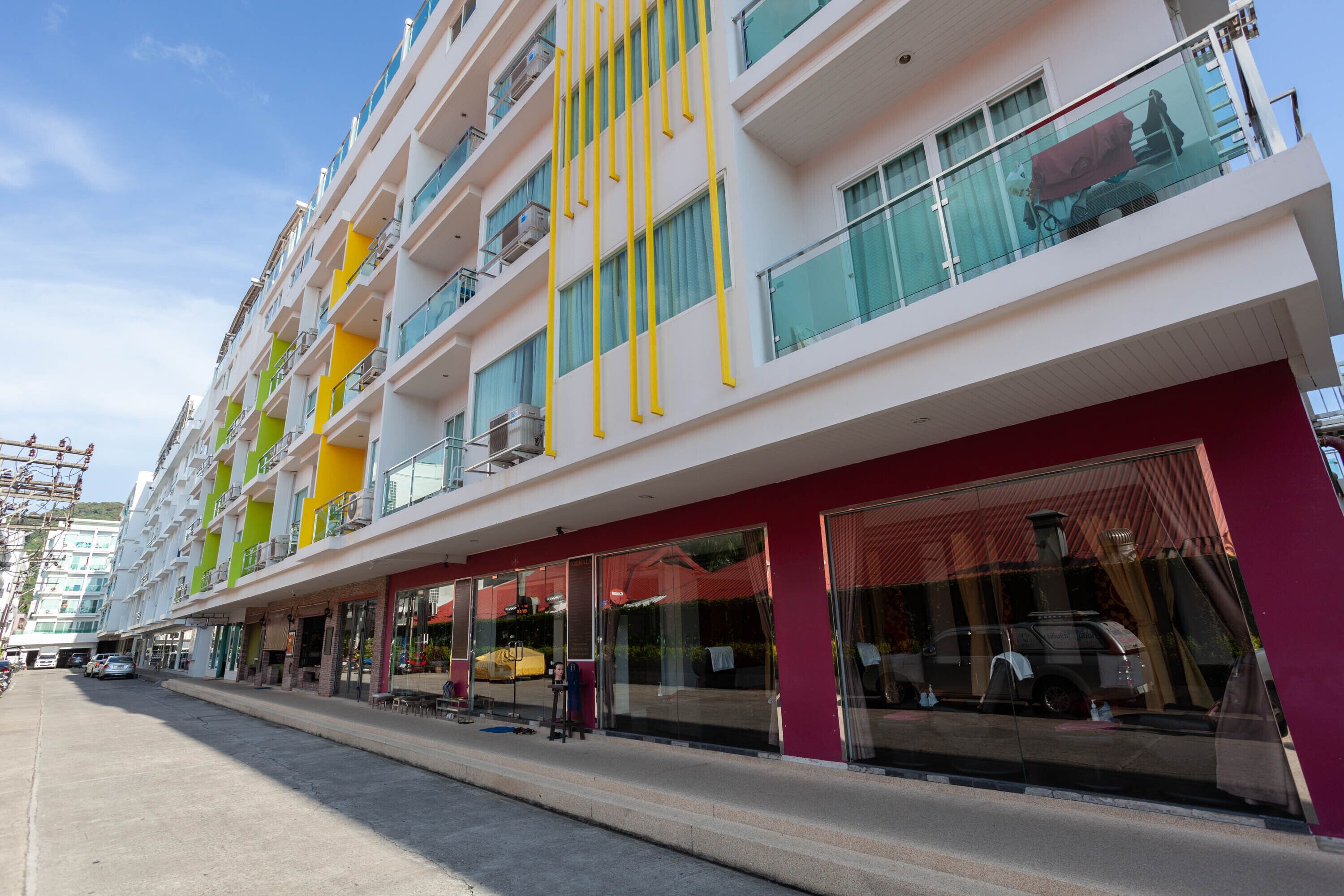 A multi-story hotel with balconies, large windows, and a red facade.