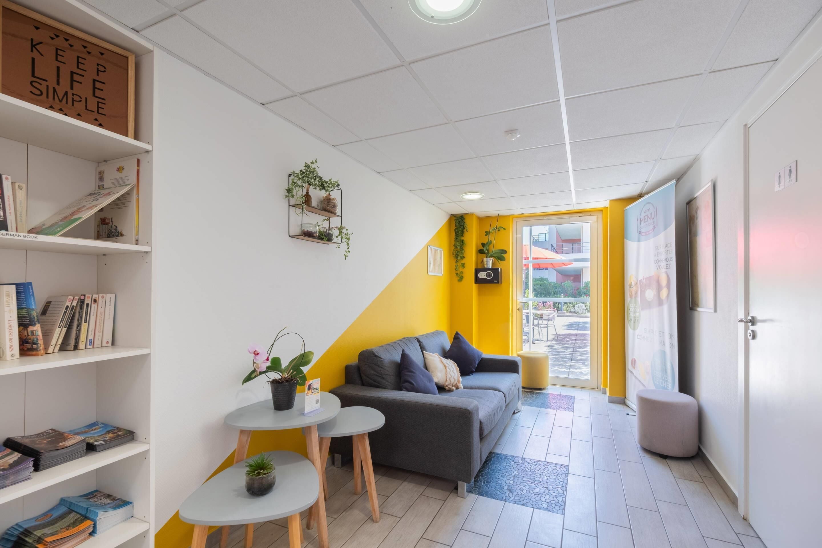 Una habitación moderna con sofá, una mesita, una estantería y una planta en maceta.