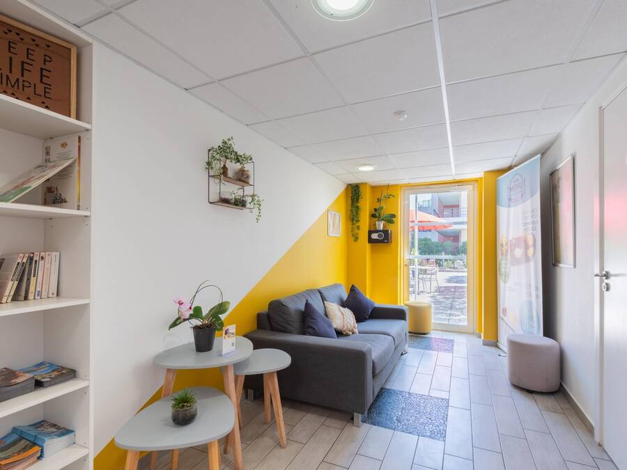 Una habitación moderna con sofá, una mesita, una estantería y una planta en maceta.