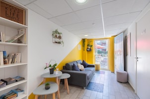 Una habitación moderna con sofá, una mesita, una estantería y una planta en maceta.