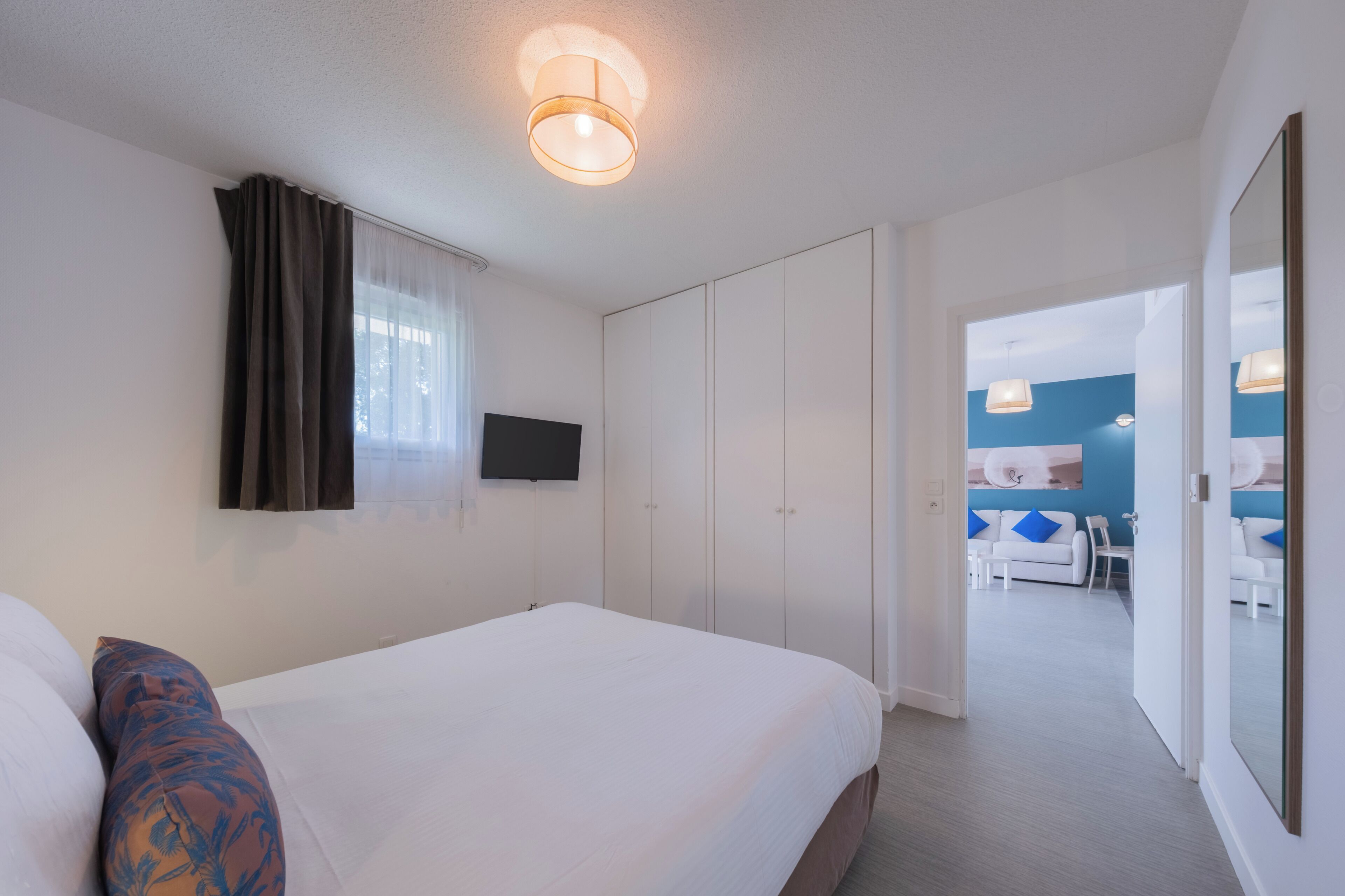 Une chambre d’hôtel comprenant un lit, une télévision, une armoire et donnant sur un espace repas.