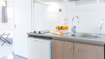 A modern kitchen with a built-in microwave, a bread basket, and a fruit bowl on the counter.