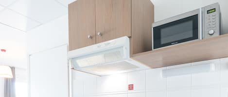 Una cocina moderna con microondas integrado, una cesta de pan y un frutero sobre la encimera.