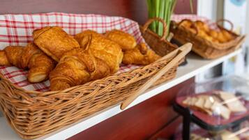 A wicker basket filled with croissants on a checkered cloth, placed on a shelf.