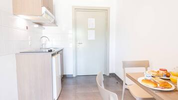 Una cocina con un lavamanos, armarios y una zona de comedor con una mesa dispuesta para el desayuno.