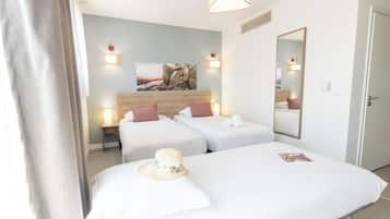 A hotel room with two beds, a wooden headboard, a mirror, and a painting on the wall.