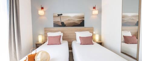 A hotel room with two beds, a large mirror, a painting on the wall, and a view of the mountains.