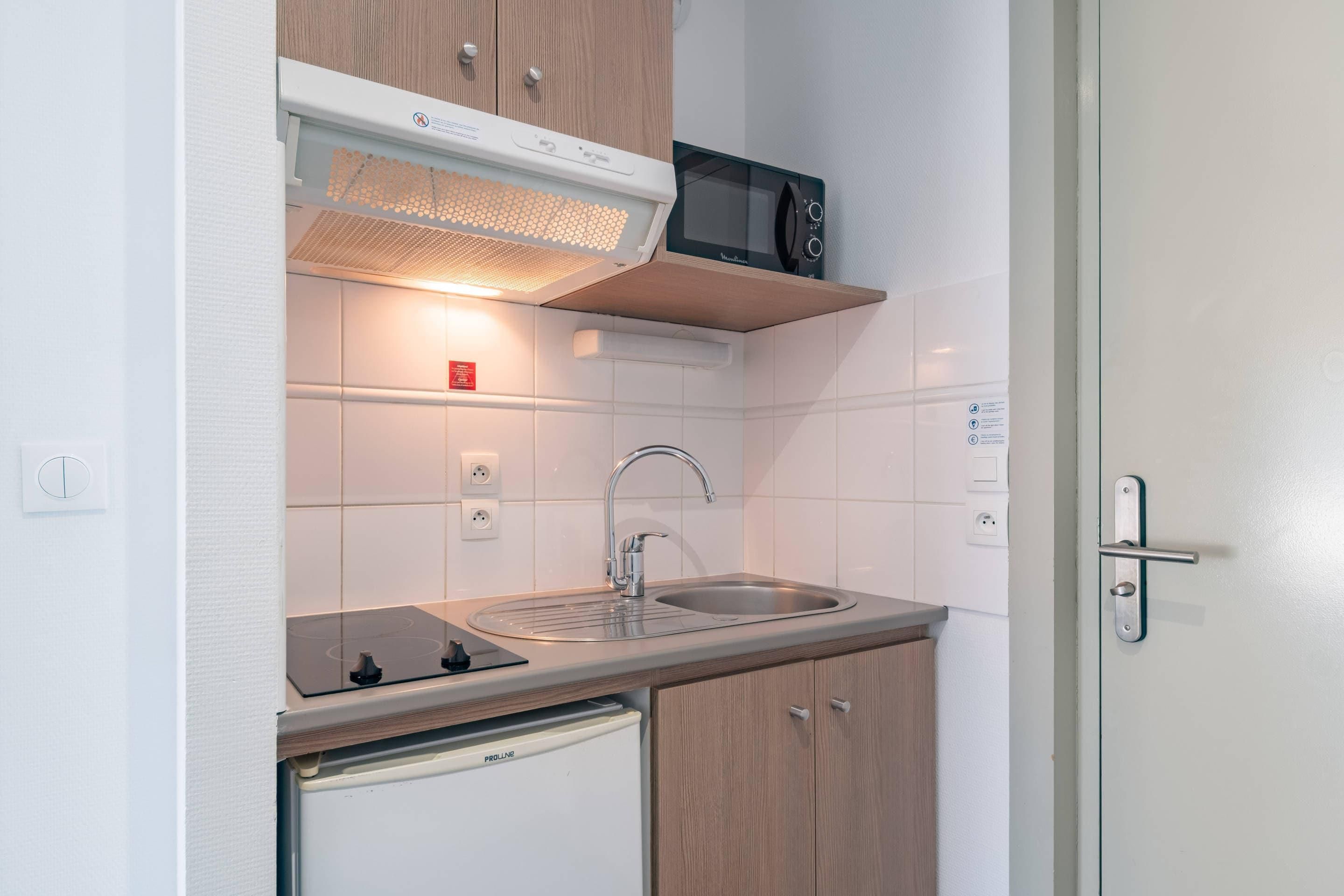 A compact kitchen with a microwave, sink, and dishwasher.
