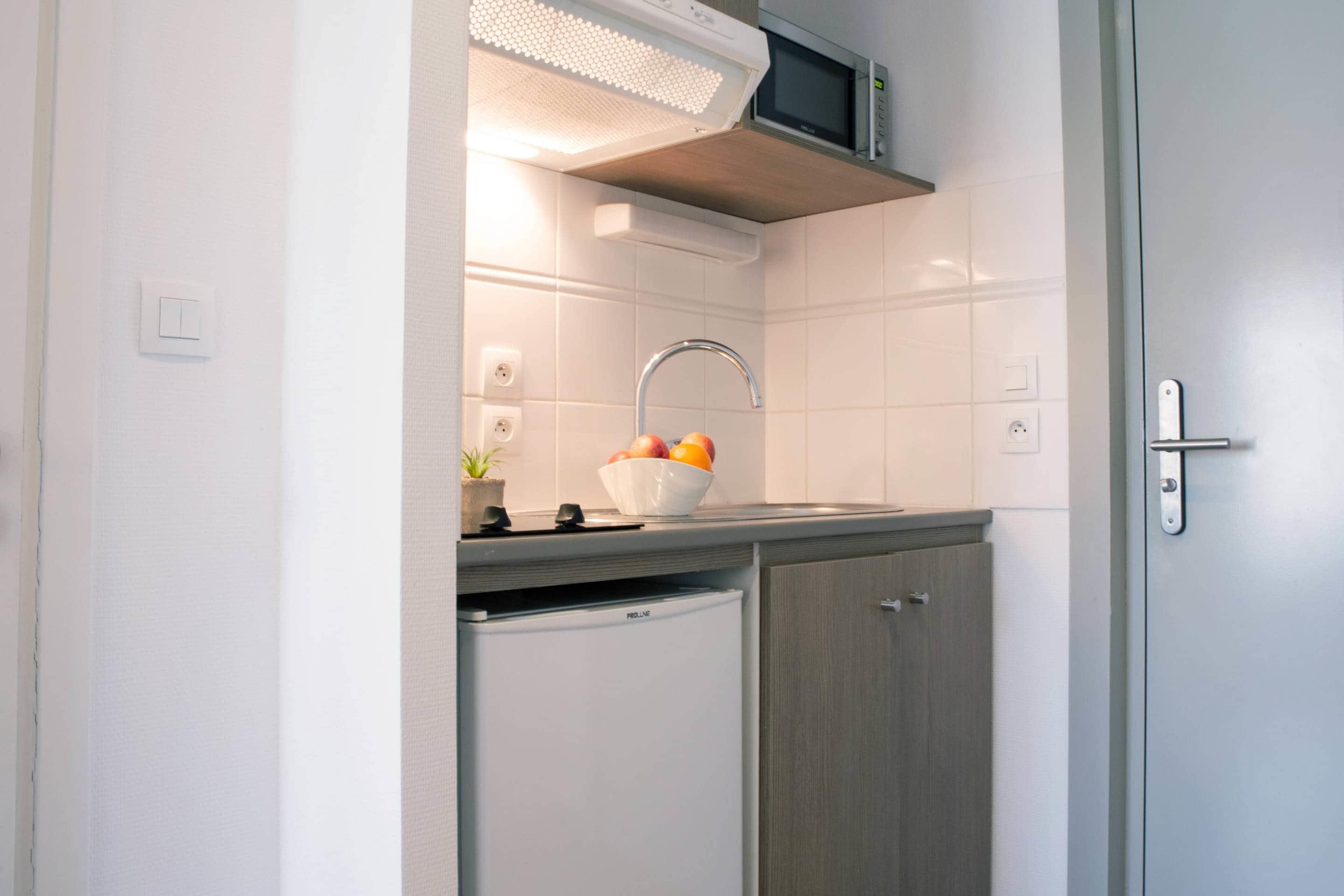 A kitchen with a microwave, sink, and a small refrigerator.